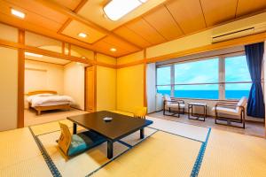 Zimmer mit einem Bett und einem Tisch sowie einem Schlafzimmer in der Unterkunft Umino Hotel Hajime - former Umikaoru Yado Hotel New Matsumi in Beppu