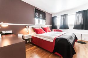 Schlafzimmer mit einem Bett mit roten Kissen und einem Schreibtisch in der Unterkunft Dolmsundet Hotell Hitra in Melandsjøen