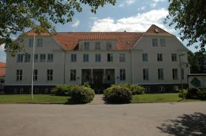 duży biały budynek z czerwonym dachem w obiekcie Katrinebergs Folkhögskola B&B w mieście Vessigebro