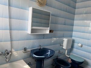 La salle de bains est pourvue de carrelage bleu, d'un lavabo et de toilettes. dans l'établissement Apartmani Infinity, à Sukošan