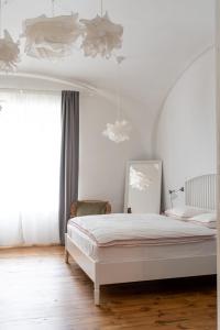 Habitación blanca con cama y ventana en FAJRONT - krásny historický byt v srdci Kremnice, en Kremnica
