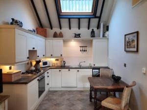 a kitchen with white cabinets and a wooden table at The Shippon, Parc yr Odyn, Pentraeth, Anglesey LL75 8UL in Pentraeth