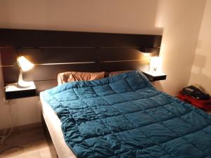 a bed with a blue comforter in a room at Apartament in complex rezidential cu parcare. in Timişoara