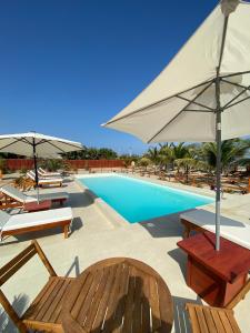 a swimming pool with chairs and umbrellas at El Samay Hotel Boutique in Canoas de Punta Sal