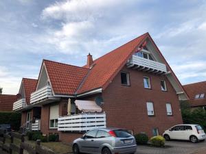 a house with a red roof and two cars parked in front at Appartement Bali in Hüllhorst
