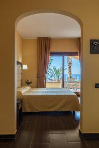 a bedroom with a bed and a view of the ocean at Hotel Cannamele Resort in Parghelia