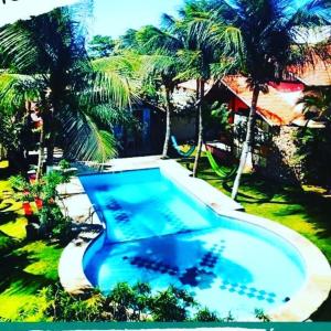 una gran piscina con palmeras en un patio en Pousada Refúgio do Manatí, en Canoa Quebrada