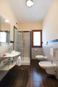ein Badezimmer mit 2 Waschbecken, einer Dusche und 2 WCs in der Unterkunft Hotel Cannamele Resort in Parghelia