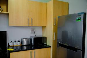 a kitchen with wooden cabinets and a stainless steel refrigerator at Sanctuary Aparthotel-AC-Garden- Solar-Wi-Fi -Firepit-Park-Carport in Lusaka