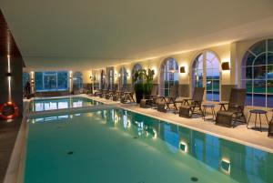 une grande piscine avec des chaises et des tables dans un bâtiment dans l'établissement Château d'Isenbourg & SPA, à Rouffach