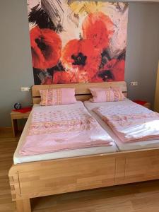 ein Holzbett mit roten Blumen an der Wand in der Unterkunft Sonnigesüdeifel in Seffern