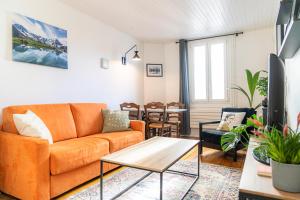a living room with an orange couch and a table at Les Échoppes in Annecy