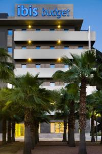 a building with palm trees in front of it at Ibis Budget Sevilla Aeropuerto in Seville