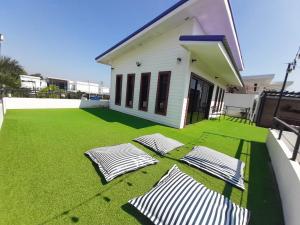 een achtertuin met groen gras en een wit huis bij Namcha Private Pool Villa Huahin 4 Bedrooom With Pool Table BBQ & Karaoke in Hua Hin