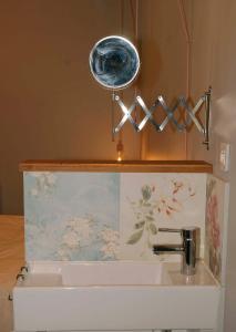 a bathroom sink with a light above it at Le Caribou d'Eva in Portbail