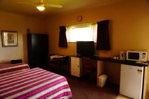 a bedroom with a bed and a desk with a microwave at Muswellbrook Northside Bed & Breakfast in Muswellbrook