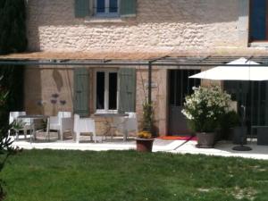 a house with a patio with chairs and an umbrella at L'Esperluette in Suze-la-Rousse