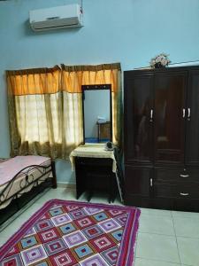 Schlafzimmer mit einem Bett, einer Kommode und einem Spiegel in der Unterkunft Homestay Zulaika Kota Aur in Kepala Batas