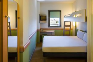 a hotel room with two beds and a mirror at Ibis Budget Sevilla Aeropuerto in Seville