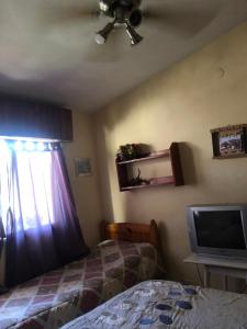 Schlafzimmer mit einem Bett, einem TV und einem Deckenventilator in der Unterkunft Alquiler de Casa en La Falda in La Falda