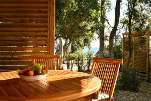 un bol de fruta en una mesa de madera en un porche en BAGHEERA Village Naturiste en Linguizzetta