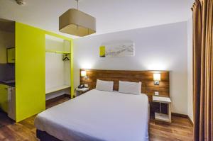 1 dormitorio con cama blanca y pared amarilla en The Originals Résidence, Grenoble Université en Saint-Martin-dʼHères