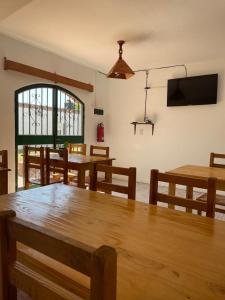 Un comedor con mesas de madera y un televisor de pantalla plana. en Hosteria EL PARRAL, en Mina Clavero