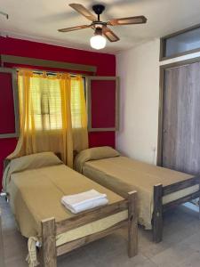Un dormitorio con dos camas y un ventilador de techo. en Hosteria EL PARRAL, en Mina Clavero