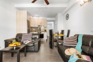 a living room with leather couches and a kitchen at Panoramic 2 Bed Penthouse in Los Cristianos