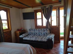 a bedroom with a couch and a bed and windows at Sol y Luna Villa Campestre in Iza
