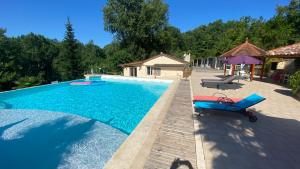 Luxury family villa in the heart of Gascony. Large pool & gorgeous view في Tourdun: مسبح مع كرسي وطاولة