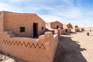 a row of buildings in a desert with a sky at Berber Camp & Desert Tours in Mhamid