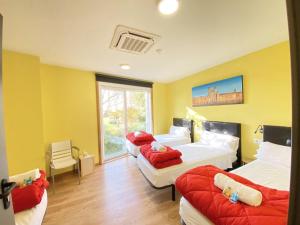 um quarto com três camas com almofadas vermelhas em Cruce De Caminos Arzua em Arzúa