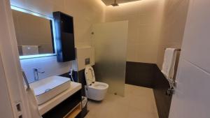 a bathroom with a white toilet and a sink at Grande Beach in Al Khīrān