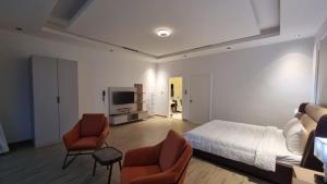a bedroom with a bed and two chairs and a television at Grande Beach in Al Khīrān