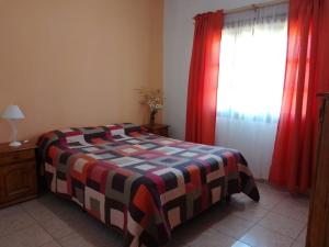 Un dormitorio con una cama y una ventana con cortinas rojas. en cabaña alojamiento Canto de las Aves, en San Rafael 36 fotos más