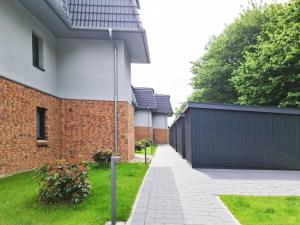 a brick house with a fence and a driveway at Zum Meer in Damp