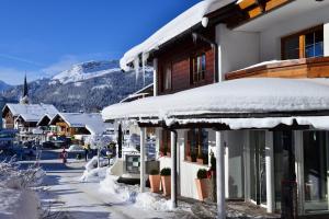 uma cidade com edifícios cobertos de neve e uma montanha em Hotel Jagdhof em Riezlern