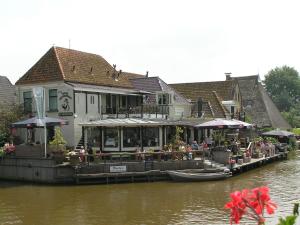 un grupo de personas sentadas en un restaurante en un río en Hotel Restaurant De Stadsherberg, en Franeker