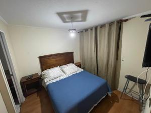 1 dormitorio con 1 cama azul y 1 silla en Departamento a pasos de Mall Plaza, en Antofagasta