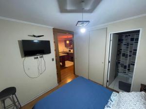a bedroom with a bed and a tv on the wall at Departamento a pasos de Mall Plaza in Antofagasta