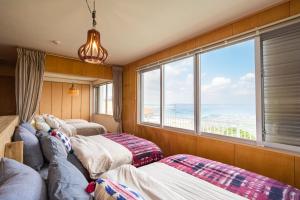 two beds in a room with a large window at SEA VIEW HOUSE KIRA KIRA HINANO in Nanjo
