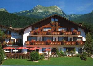 a building with red umbrellas in front of a mountain at Ferienhotel Barmsee in Krün