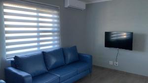sala de estar con sofá azul y TV en Elephant House, 2 bedroom House, Next to Pilanesberg and Sun City en Mogwase