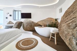 a bedroom with a bathtub and a large rock formations at Teal Rock Mykonos in Ano Mera +119 photos
