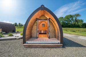 una pequeña casa hobbit de madera con puerta de madera en Parc Maerdy Glamping Holidays en New Quay