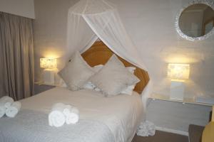 a bedroom with a bed with white sheets and pillows at Valentines Hermanus in Hermanus
