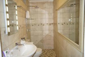 a bathroom with a sink and a toilet and a mirror at Valentines Hermanus in Hermanus