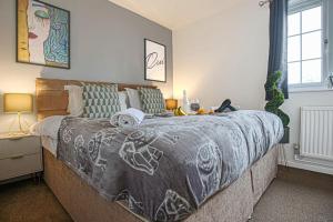 a bedroom with a large bed with a blanket at Petworth House - Central Milton Keynes - Smart TVs, Pool Table, Garden and Free Parking by Yoko Property in Milton Keynes