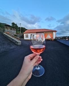 une personne tenant un verre de vin dans l'établissement Lucy's Rosegarden, à Urzelina